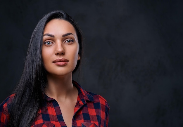 Retrato de estudio de mujer hipster glamour morena vestida con una camisa de lana roja sobre fondo gris.