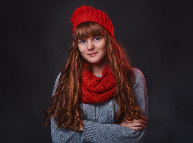 Retrato de estudio de mujer pelirroja con ropa de abrigo posando sobre fondo gris.