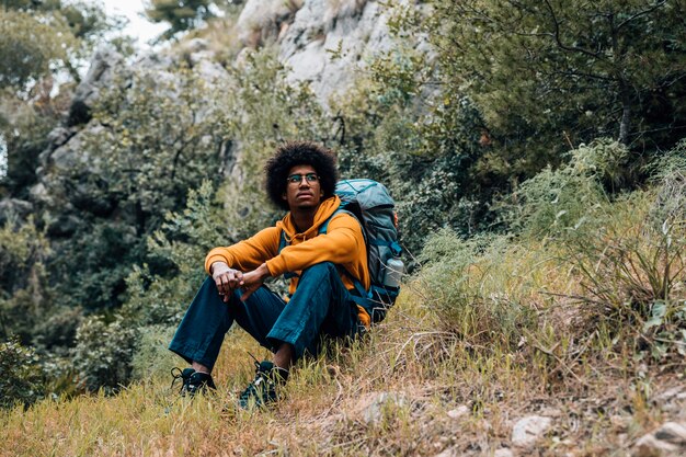 Retrato de un excursionista masculino africano sentado descansando en la montaña