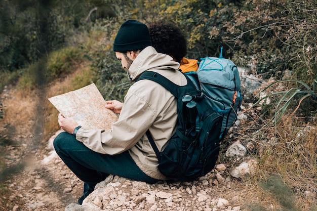 Retrato de un excursionista masculino mirando el mapa sentado con su amigo