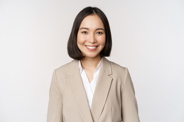 Retrato de una exitosa mujer de negocios con traje sonriendo y luciendo como profesional en el fondo blanco de la cámara