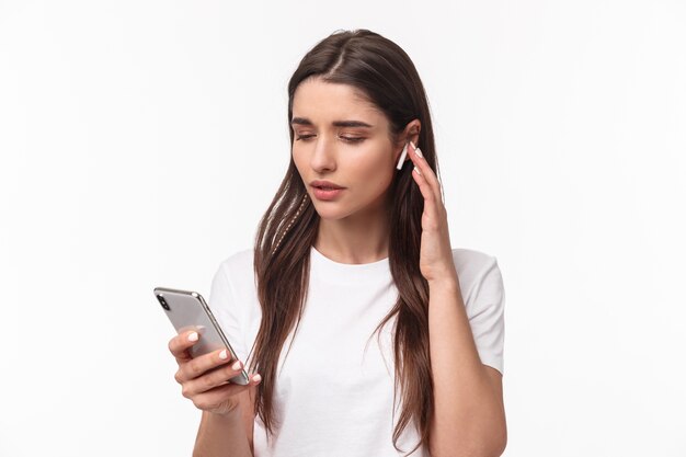 retrato, expresivo, mujer joven, con, airpods, y, móvil