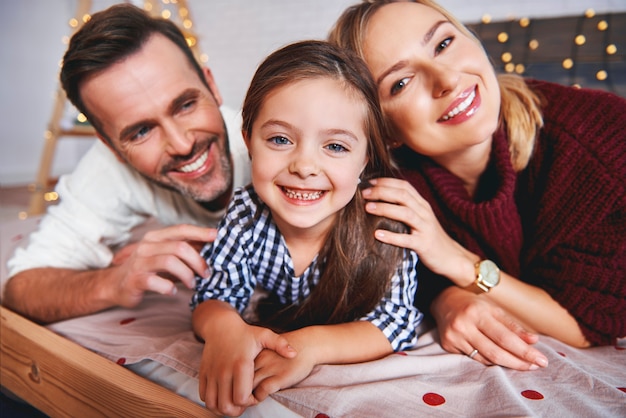 Retrato de familia acostada en la cama en Navidad