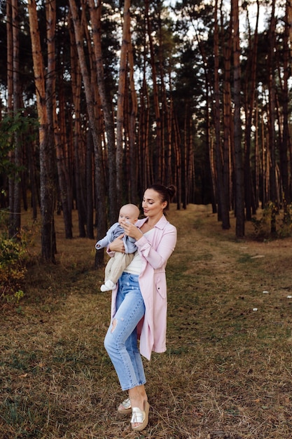 Retrato de familia atractiva joven con hijo pequeño, posando en el hermoso bosque de pinos de otoño en un día soleado. Hombre guapo y su bella esposa morena