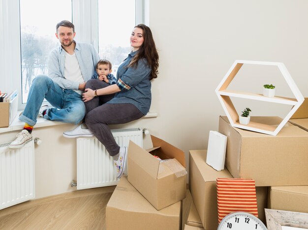 Retrato de una familia con cajas de cartón en movimiento en su nuevo hogar.