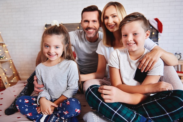 Retrato de familia feliz en la cama en Navidad