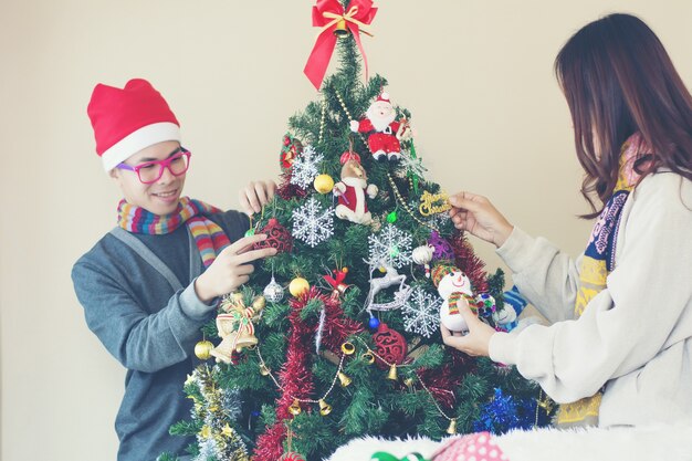 Retrato de familia feliz decorando el árbol de Navidad