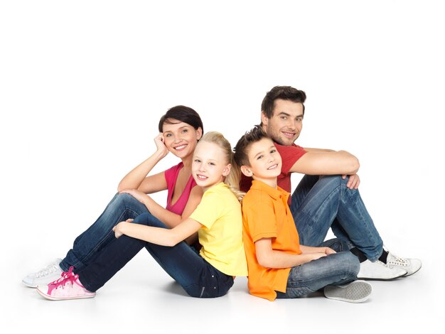 Retrato de la familia feliz con dos niños sentados en el estudio en el piso blanco