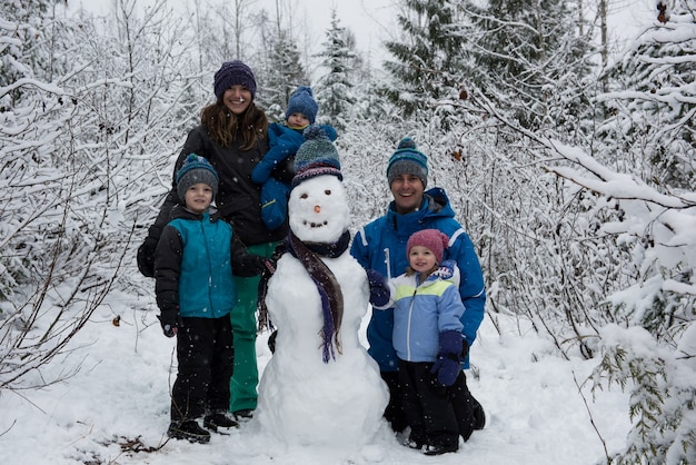 Foto gratuita retrato de familia feliz de pie por muñeco de nieve