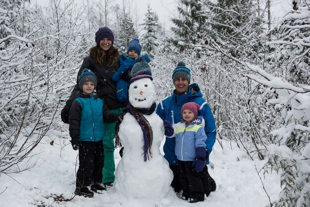 Retrato de familia feliz de pie por muñeco de nieve