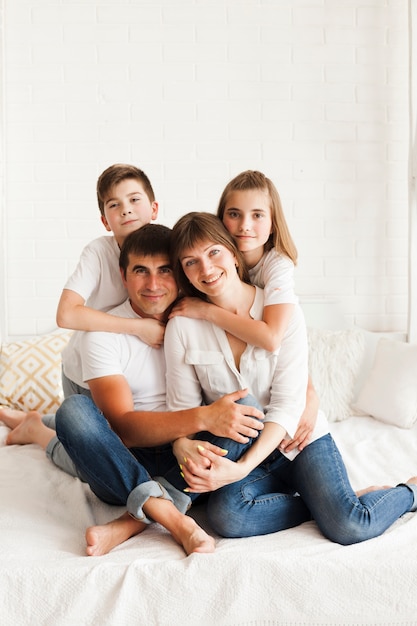 Retrato de familia feliz sentado en la cama en su casa