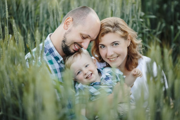 Retrato de familia hermosa entre el campo de trigo