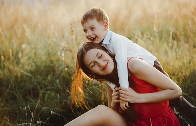 Retrato de familia, naturaleza. Encantadora madre e hijo juegan en el césped b