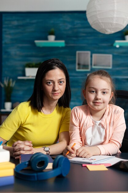 Retrato de familia sonriente mirando a la cámara mientras está sentado en un escritorio