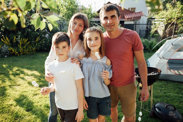 Retrato de familia sonriente sosteniendo malvavisco en picnic