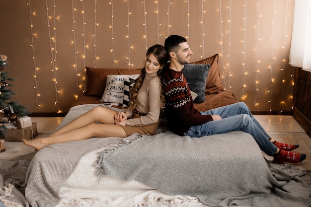 Retrato familiar. El hombre y la mujer se relajan en un gris suave en una habitación con un árbol de Navidad