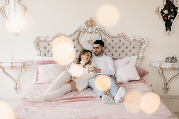 Retrato familiar. El hombre y la mujer se relajan en un gris suave en una habitación con un árbol de Navidad