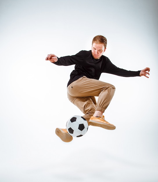 Un retrato de un fan con la bola en fondo gris del estudio. Freestile