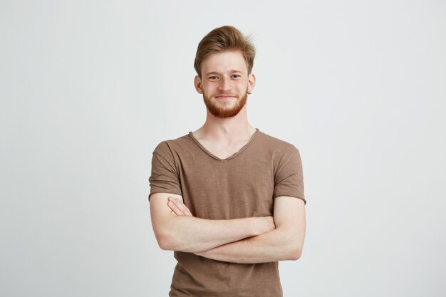 Retrato de feliz alegre joven con barba sonriendo con los brazos cruzados.