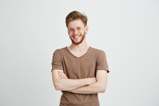 Retrato de feliz alegre joven con barba sonriendo con los brazos cruzados.