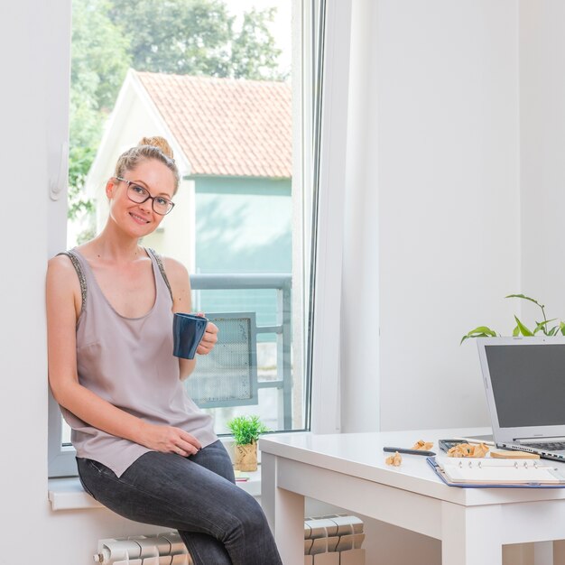 Retrato de una feliz empresaria sentado con una taza de café