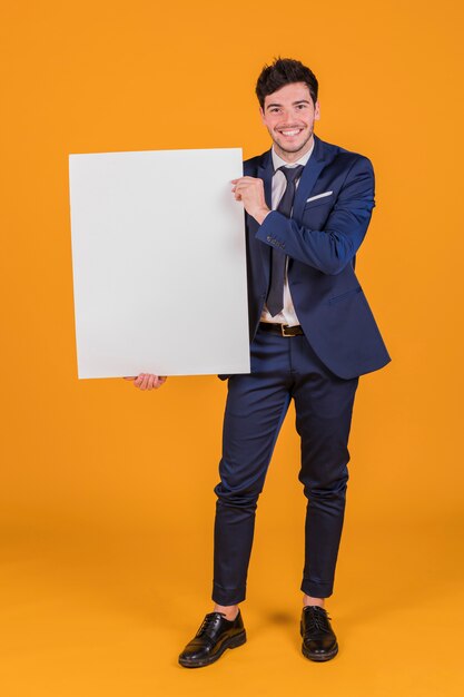 Retrato feliz de un hombre de negocios joven que muestra el cartel en blanco blanco que se sostiene a disposición