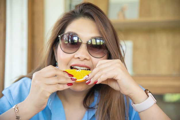 Retrato feliz joven asiática comiendo naranja