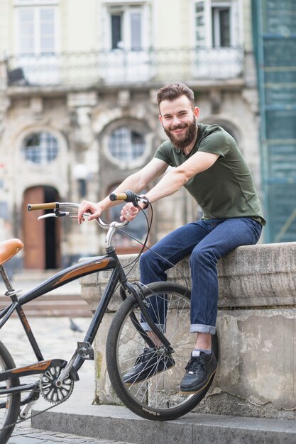 Retrato de un feliz joven ciclista masculino con bicicleta