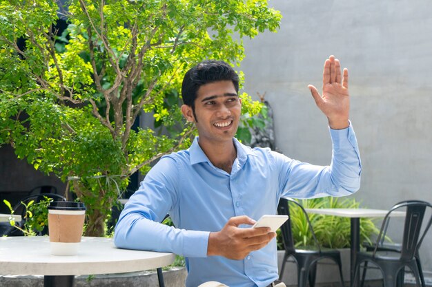 Retrato de feliz joven empresario saludo colega al aire libre.