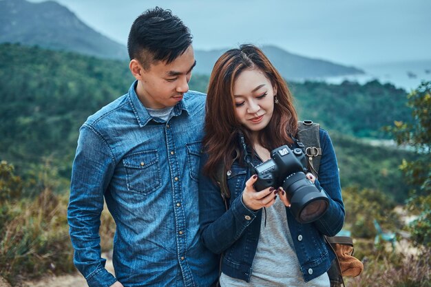 Retrato de feliz joven pareja asiática. Están viendo fotos en una cámara digital. Tienen un estilo casual.