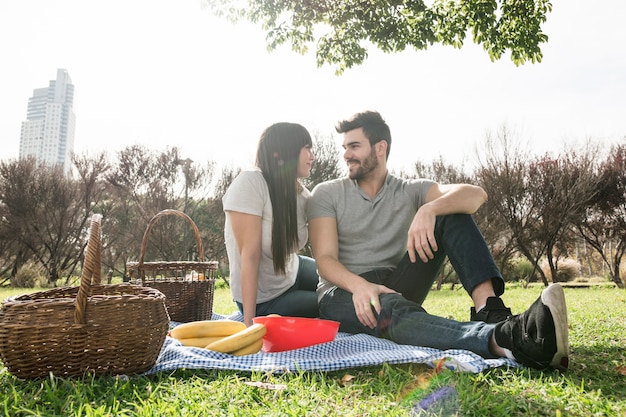 Retrato feliz de la joven pareja disfrutando en el picnic