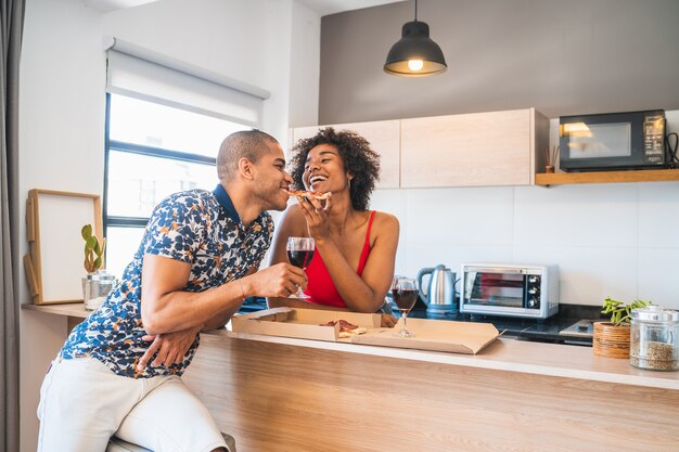 Retrato de feliz joven pareja latina disfrutando y cenando en casa nueva. Concepto de estilo de vida y relación.