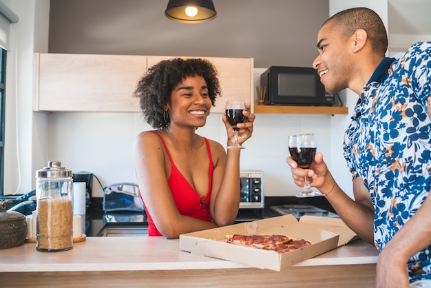 Retrato de feliz joven pareja latina disfrutando y cenando en casa nueva.