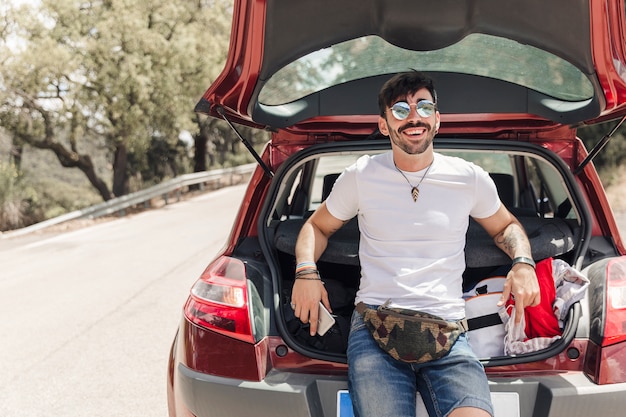 Retrato de feliz joven de pie cerca del coche en la carretera