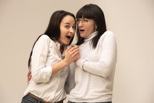 Un retrato de una feliz madre e hija en el estudio en gris