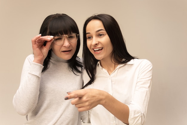 Un retrato de una feliz madre e hija en el estudio en gris