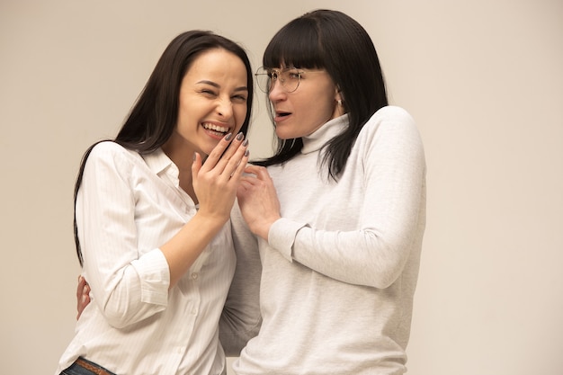 Un retrato de una feliz madre e hija en el estudio sobre fondo gris. Concepto de expresiones faciales y emociones positivas humanas