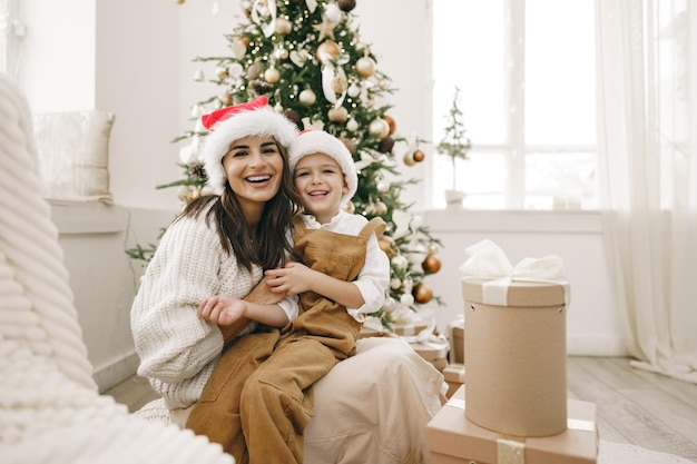 Retrato de feliz madre y su hijo celebran la Navidad en una sala decorada festivamente