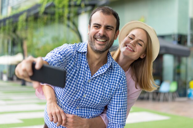 Retrato de feliz mediados de pareja adulta teniendo foto con teléfono móvil.