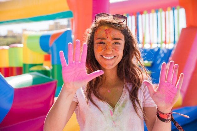 Retrato feliz de una mujer joven que muestra las manos del color del holi