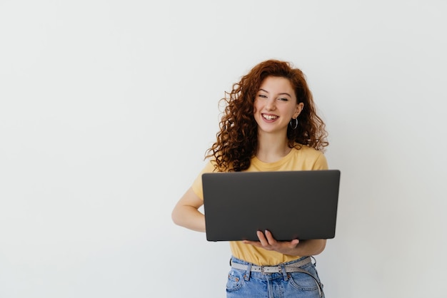 retrato, de, feliz, mujer joven, tenencia, computador portatil, en, un, fondo blanco