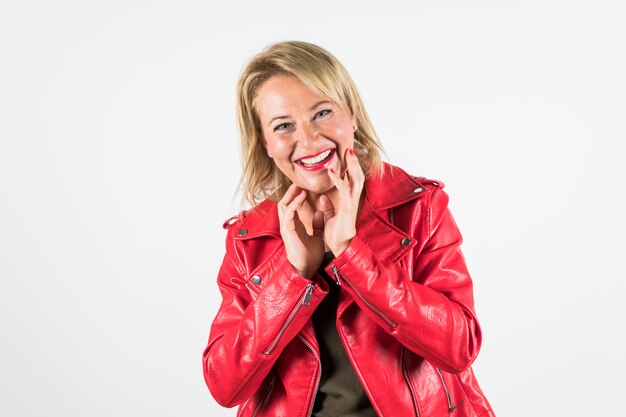 Retrato feliz de la mujer madura en la chaqueta roja aislada en el contexto blanco