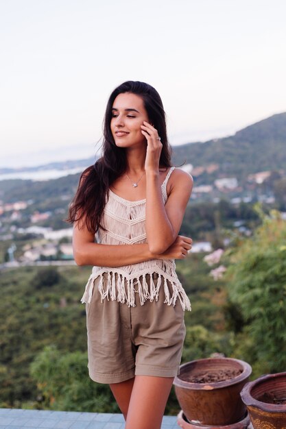 Retrato de feliz mujer romántica tranquila caucásica en look casual con el pelo largo con aretes y collar sobre fondo increíble vista hermosa en montañas verdes