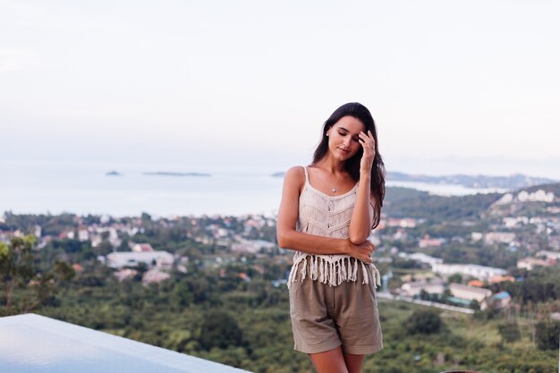 Retrato de feliz mujer romántica tranquila caucásica en look casual con el pelo largo con aretes y collar sobre fondo increíble vista hermosa en montañas verdes