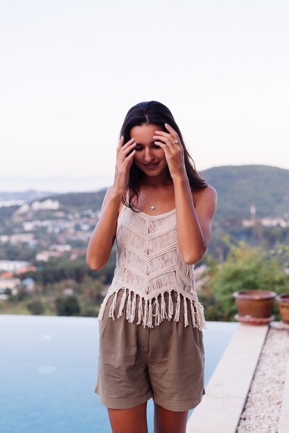 Retrato de feliz mujer romántica tranquila caucásica en look casual con el pelo largo con aretes y collar sobre fondo increíble vista hermosa en montañas verdes