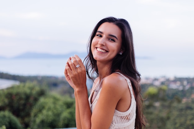 Retrato de feliz mujer romántica tranquila caucásica en look casual con el pelo largo con aretes y collar sobre fondo increíble vista hermosa en montañas verdes