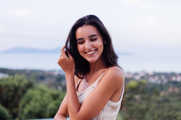 Retrato de feliz mujer romántica tranquila caucásica en look casual con el pelo largo con aretes y collar sobre fondo increíble vista hermosa en montañas verdes