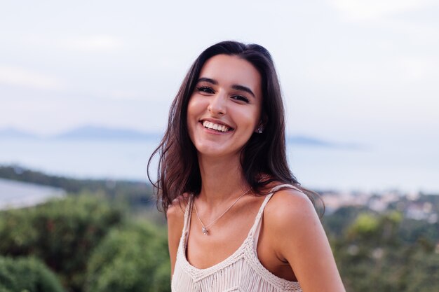 Retrato de feliz mujer romántica tranquila caucásica en look casual con el pelo largo con aretes y collar sobre fondo increíble vista hermosa en montañas verdes