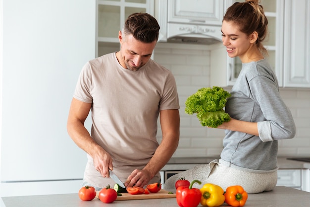 Retrato de una feliz pareja amorosa cocinar ensalada juntos