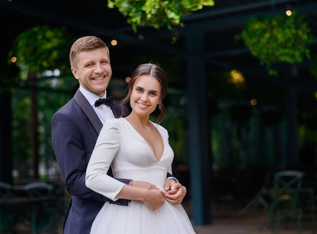 Retrato de feliz pareja amorosa esposo y esposa en la ceremonia de la boda abrazando Hermosa novia en vestido hinchado con novio en traje elegante Familia feliz Pareja casada Día de la boda